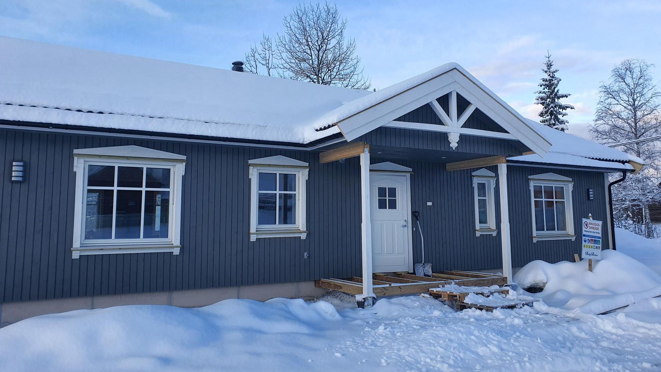 Blå hytte med hvite detaljer i snølandskap